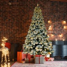 a decorated christmas tree in front of a brick wall with presents under it and lights on