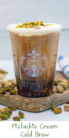 a cup of coffee with pistachio cream on top and nuts around the bottom