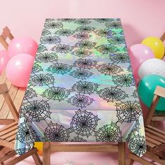 the table cloth has spider webs on it and balloons are in the corner behind it