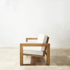 a wooden chair sitting on top of a tile floor next to a white wall in an empty room