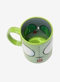 a green coffee cup with an alien face on the front and bottom, sitting against a white background