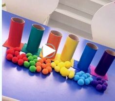 a table topped with lots of colorful pom poms next to rolls of toilet paper