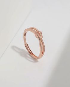 a rose gold ring with an intertwined design on the band and two diamonds in the middle