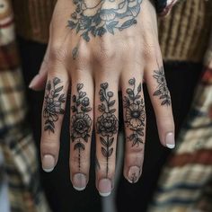 a woman's hand with tattoos and flowers on it