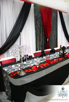 a black and white table with red flowers on it is set up for an event