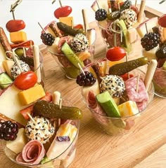 many different types of appetizers are arranged in small bowls on a wooden table