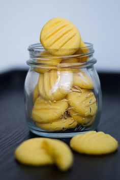 a glass jar filled with yellow cookies on top of a table