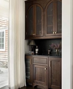 a kitchen with wooden cabinets and white curtains