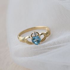 Delicate and symbolic Claddagh ring is made out of 14k solid gold and set with blue heart topaz and diamond It would make a perfect choice for the engagement or as a push gift. Ring can be made in white, rose or yellow 14k gold. Highly polished. If you want to customise this product or set it with another stones - please write to us. ❤ Hand Made with love in our studio in Prague ❤ Stone details Topaz Shape: Heart Dimensions: 5.7 mm Color: Blue Origin: Natural Diamond Amount: 1 Shape: Round Color Blue Topaz Diamond Promise Ring With Birthstone, 14k Gold Topaz Birthstone Promise Ring, Promise Yellow Gold Topaz Birthstone Ring, Hallmarked Blue Topaz Birthstone Promise Ring, Heart Cut Topaz Birthstone Ring For Anniversary, Ring With Heart, Push Gifts, Claddagh Ring, Claddagh Rings