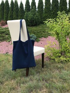 a blue and white bag sitting on top of a chair in front of some bushes