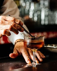 a man is holding a spoon in his hand while sitting at a bar with a drink