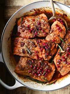 meat with pomegranates and herbs in a pan on a wooden table