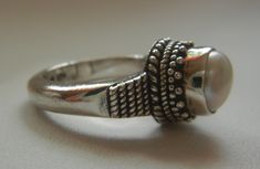 "Bali Suarti sterling silver and pearl ring. Small and beautiful, this ring has a soft iridescent white pearl, set in a raised bezel. The slightly domed pearl is encased in two rows of fine granulation pebbles and two rows of fine braiding. The sides have a striped-pebble vertical design. The back of the setting is solid and the band is thick. Beautifully made in the Balinese tradition and in excellent vintage condition. Please see detailed measurements below. > Size 5.5. *Thank you for doubl Silver Open Ring Pearl Ring, Adjustable Pearl Drop Ring, Handmade Silver Pearl Ring For Formal Occasions, Unique Sterling Silver Pearl Ring In Silver, Unique Sterling Silver Pearl Ring, Silver Rings With Pearl Drop, Unique Silver Pearl Ring For Anniversary, Adjustable Pearl Drop Round Rings, Silver Sterling Silver Pearl Ring