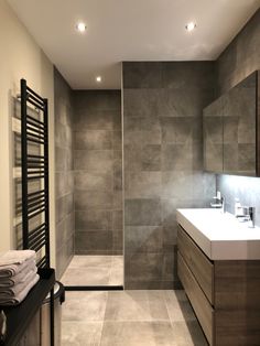 a bathroom with a sink, mirror and towel rack in it's corner next to the shower