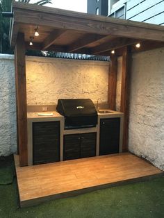 an outdoor bbq with grill, sink and cabinets under a pergolated roof