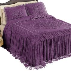 a bed with purple bedspread and pillows