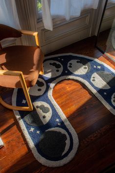 a rocking chair sitting on top of a wooden floor next to a rug covered in cartoon faces