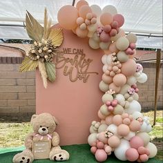 a teddy bear sitting next to a giant balloon arch