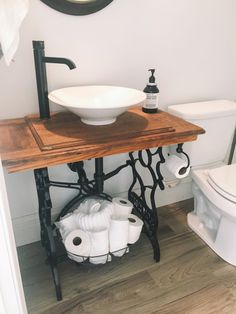 a white toilet sitting next to a wooden table with a bowl on top of it