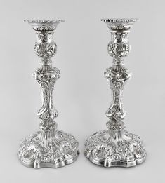 two silver candlesticks sitting next to each other