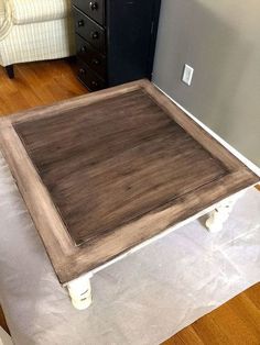 a wooden table sitting on top of a hard wood floor next to a white chair