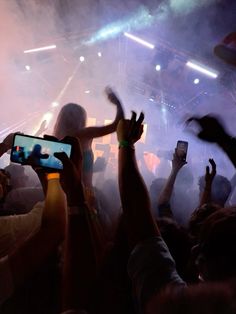 many people are taking pictures with their cell phones at a concert while the crowd is clapping