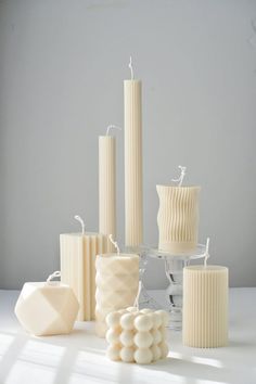 white candles and vases are arranged on a table