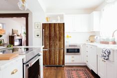 a white kitchen with wood paneling and an oven in the center, along with a rug on the floor