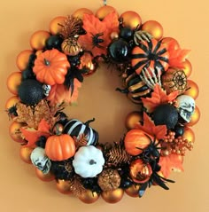 a wreath decorated with pumpkins, spider webs and other halloween decorations is hanging on the wall