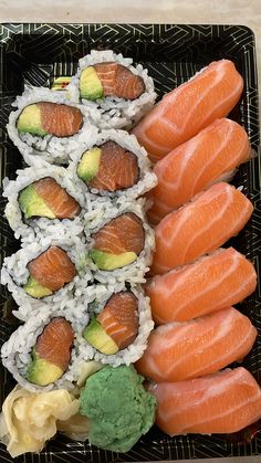 sushi is arranged on a black plate with white rice and avocado