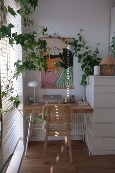 a room with a desk, chair and potted plant on the wall next to it