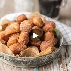 a bowl filled with donuts sitting on top of a table next to a cup of coffee