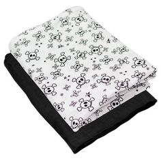 a white and black blanket with skulls on it's edges, folded up in front of a white background