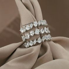 three pieces of diamond ring sitting on top of a beige cloth next to each other