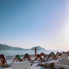 a group of people doing yoga on the roof of a building next to an ocean