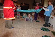 a group of children playing with a blue hammock on the floor in a living room