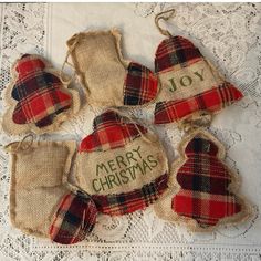 four burlap bags with christmas ornaments hanging from them on a lace tablecloth