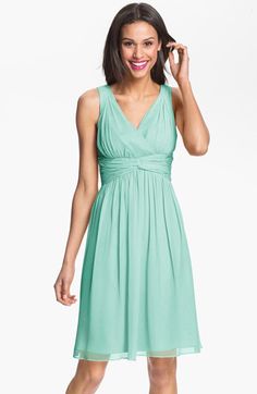 a woman in a green dress is smiling and holding her hand up to her ear