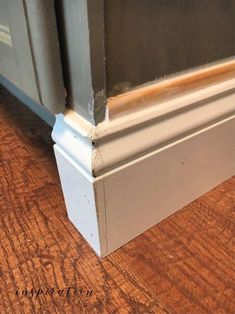 the corner of a room with wood flooring and white mold on the bottom edge