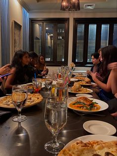 a group of people sitting around a table with food and wine glasses in front of them