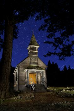 an image of a church at night with stars in the sky and trees around it