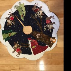 a clock made out of fabric with christmas trees and reindeers on the front, sitting on a wooden floor