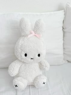 a white stuffed animal sitting on top of a bed