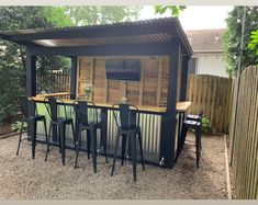 an outdoor bar with four stools and a television mounted to the side of it