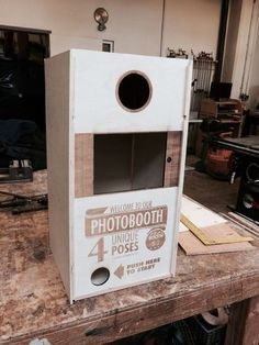 a birdhouse made out of cardboard sitting on top of a wooden table in a garage