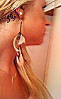 a woman with long blonde hair and tattoos on her neck is looking into the mirror