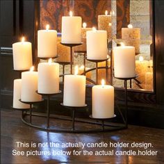 a group of white candles sitting on top of a metal stand in front of a mirror