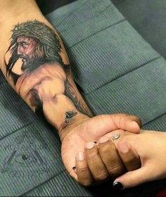 a man with a tattoo on his arm holding the hand of another person