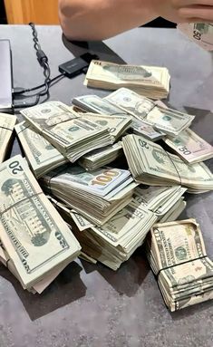 a pile of money sitting on top of a table next to a phone and keyboard