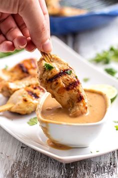 a person dipping sauce onto chicken on a stick